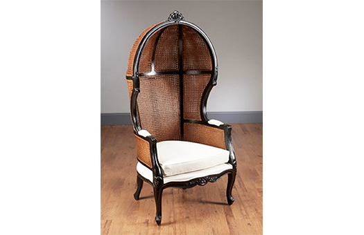 Large hood chair with dark wicker back and black wood trim and white cushion