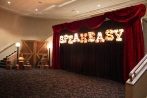 Speakeasy lit letters red velvet drape set with moonshine still vignette